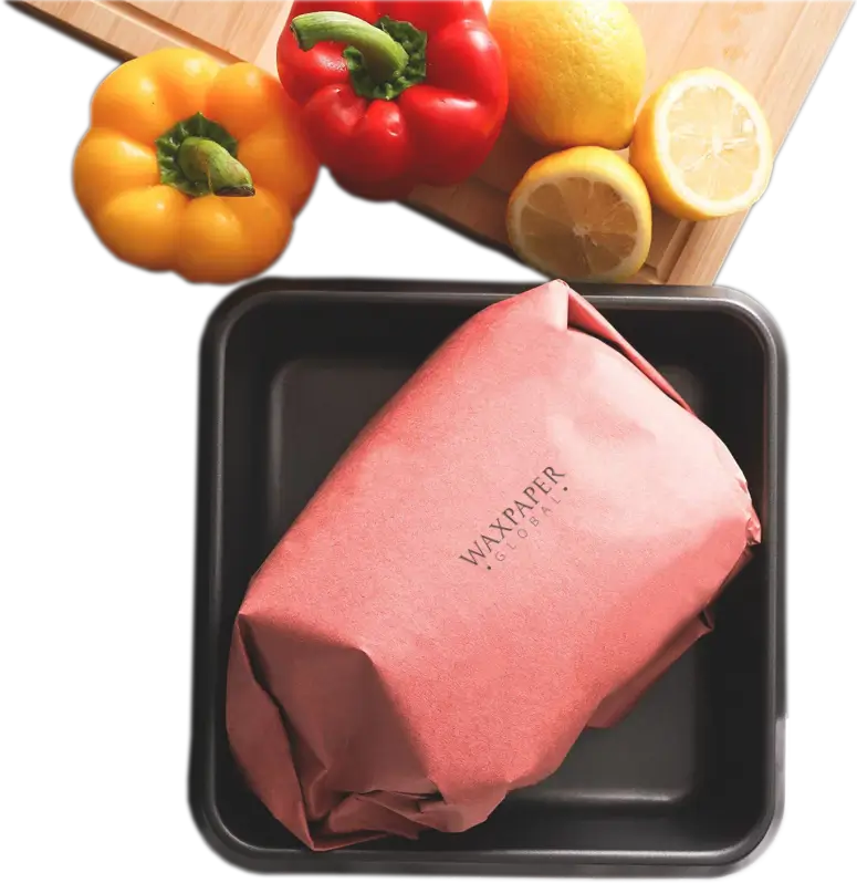 Freshly wrapped meat in custom pink butcher paper featuring the Wax Paper Global logo, placed in a black tray with lemons and bell peppers on a cutting board in the background