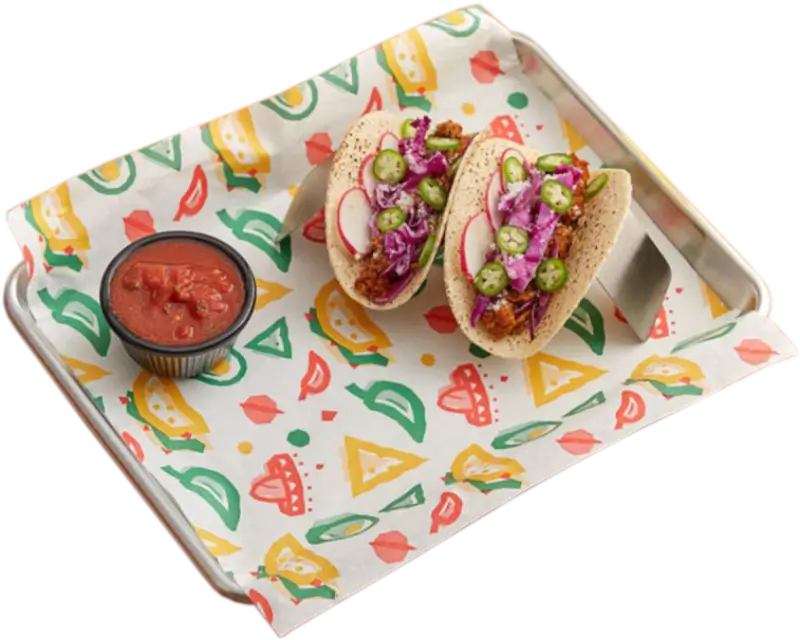 Two tacos filled with fresh toppings, served with a side of salsa on a vibrant custom-printed food paper, placed on a tray for a colorful dining experience