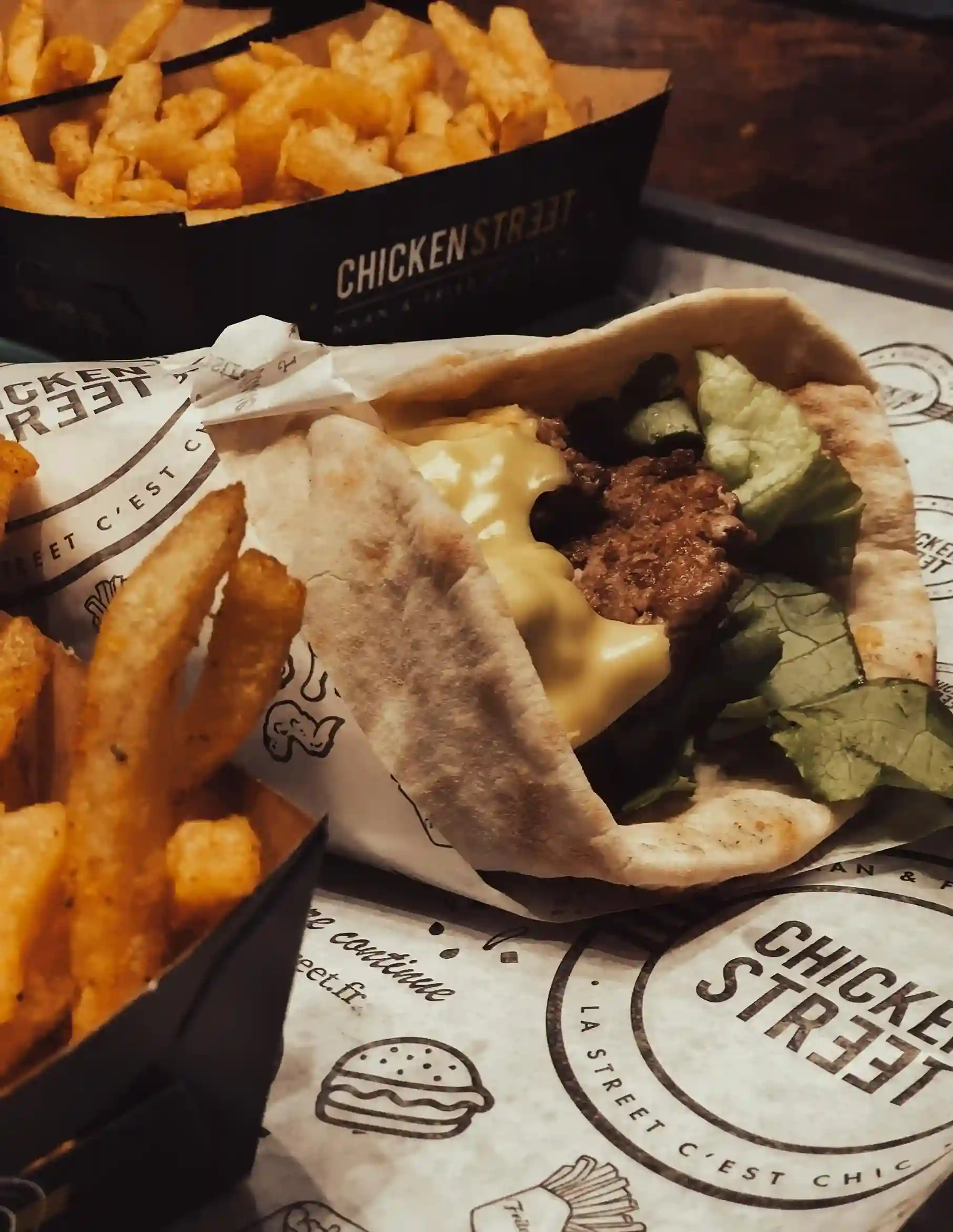 Juicy chicken wrap in custom printed wax coated paper with Chicken Street logo, served with a side of crispy fries